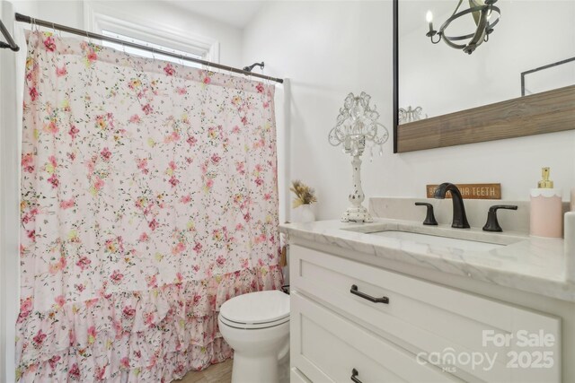 full bath with a shower with shower curtain, toilet, and vanity