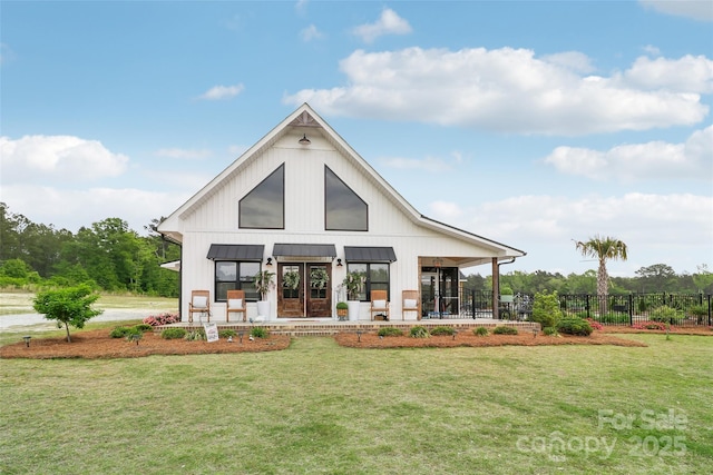 rear view of house featuring metal roof, a standing seam roof, a lawn, and fence