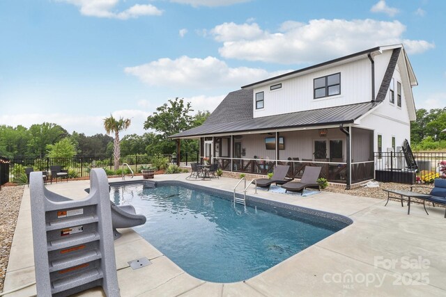 view of swimming pool featuring fence, a sunroom, a patio, and a fenced in pool
