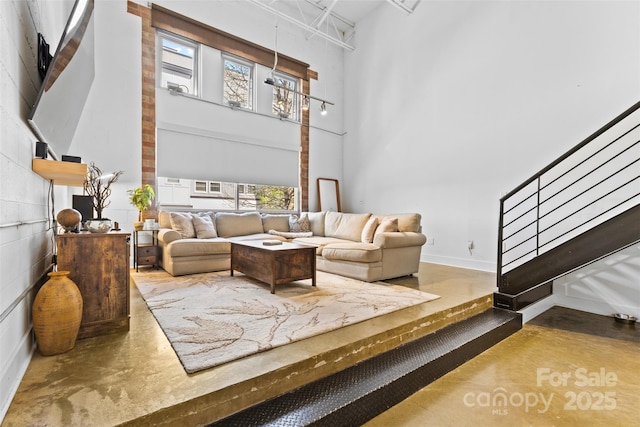 925 Westmere Ave, Charlotte, NC 28208 - living area with baseboards, stairway, a towering ceiling, and finished concrete floors
