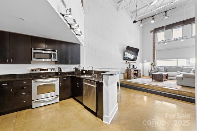 925 Westmere Ave, Charlotte, NC 28208 - kitchen featuring track lighting, dark countertops, appliances with stainless steel finishes, a sink, and a high ceiling