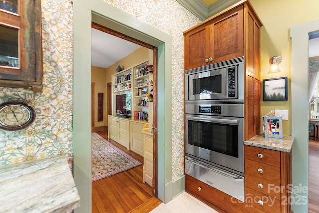 156 Cumberland Ave, Asheville, NC 28801 - kitchen with appliances with stainless steel finishes, a warming drawer, wood finished floors, light stone countertops, and brown cabinetry