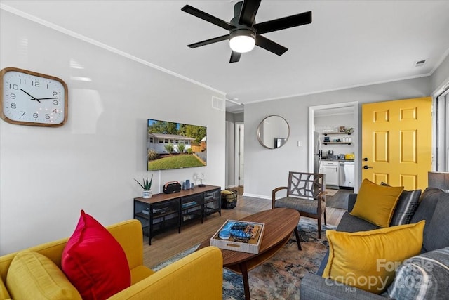 living room featuring visible vents, baseboards, ornamental molding, wood finished floors, and a ceiling fan