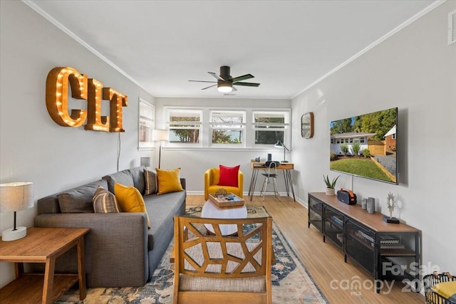 living room with visible vents, crown molding, baseboards, wood finished floors, and a ceiling fan