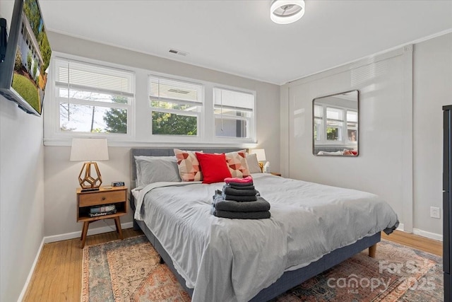 bedroom with baseboards, visible vents, and wood finished floors