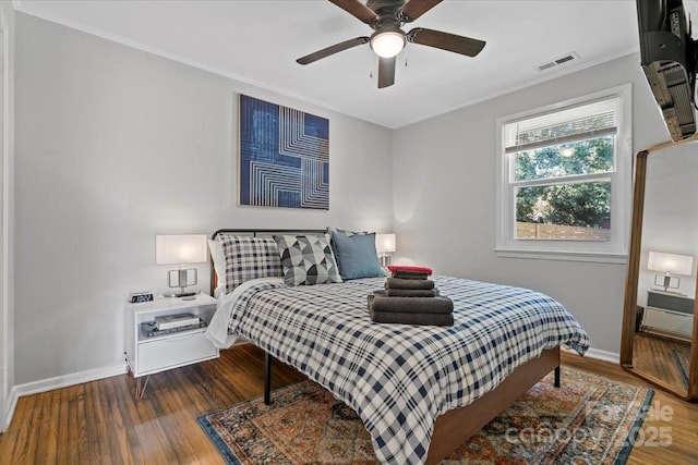 bedroom with baseboards, visible vents, wood finished floors, and ornamental molding