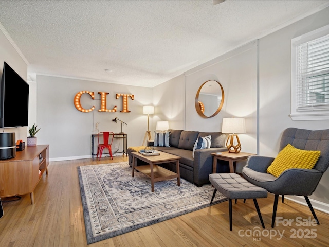 living area with baseboards, a textured ceiling, crown molding, and wood finished floors