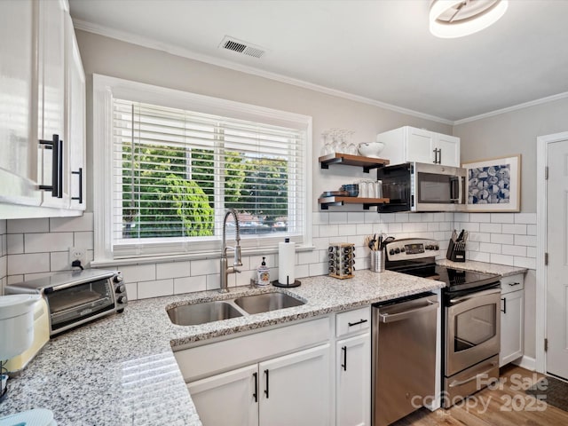 kitchen with a sink, visible vents, backsplash, and appliances with stainless steel finishes
