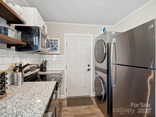 kitchen with crown molding, stacked washing maching and dryer, appliances with stainless steel finishes, and open shelves