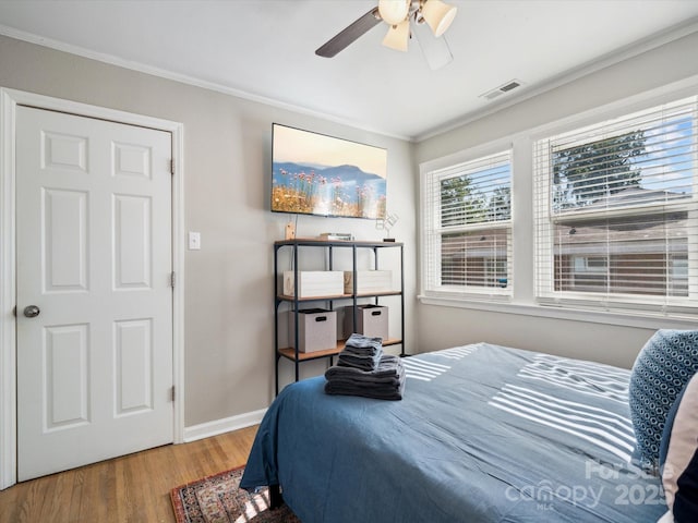bedroom with baseboards, visible vents, wood finished floors, and ornamental molding