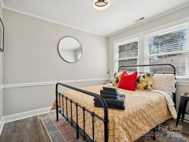 bedroom featuring baseboards, visible vents, a textured ceiling, and wood finished floors