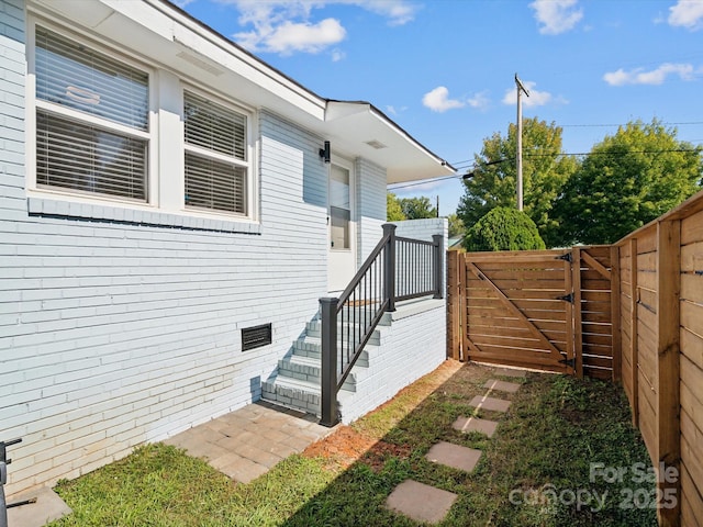 view of side of home with crawl space, a gate, and fence