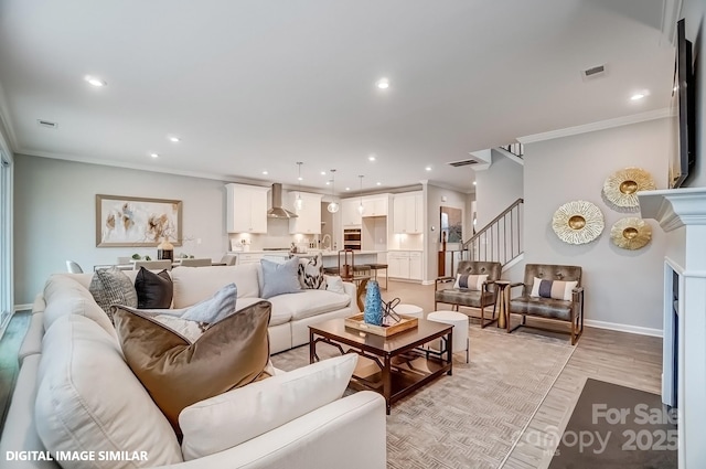 living area featuring crown molding, stairway, light wood-style flooring, baseboards, and recessed lighting