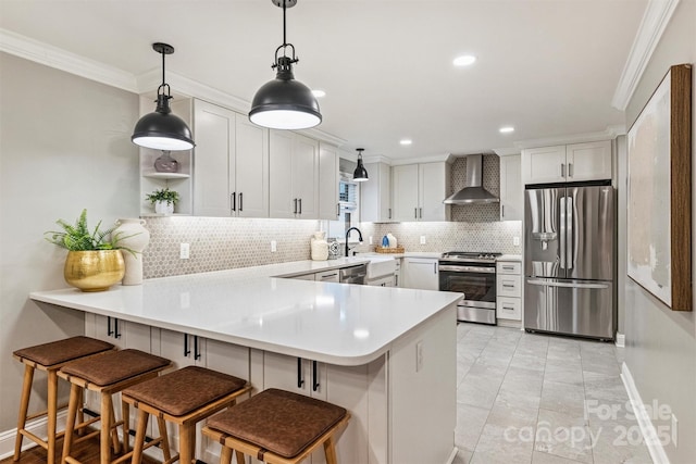 kitchen with wall chimney range hood, a peninsula, ornamental molding, and stainless steel appliances