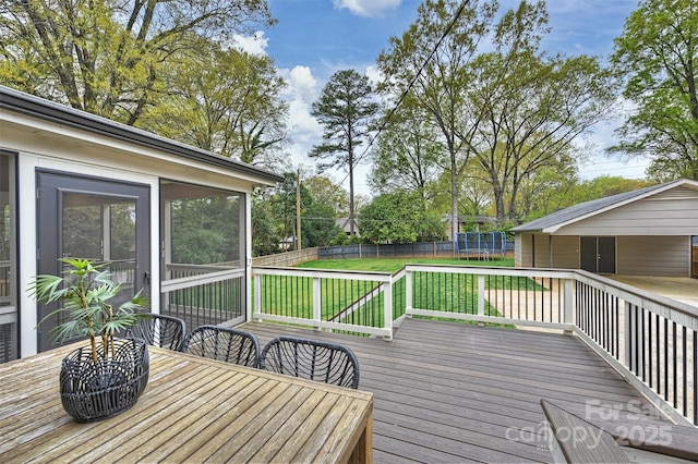 deck featuring a lawn, fence, a trampoline, and outdoor dining area