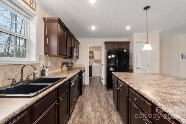 kitchen featuring dark brown cabinets, tasteful backsplash, a sink, black appliances, and washer / dryer