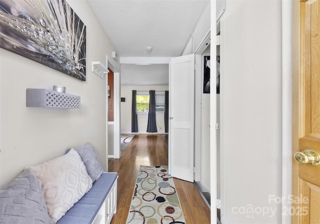 corridor with baseboards, a textured ceiling, and wood finished floors
