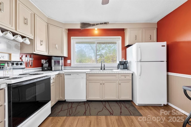 kitchen with light wood-style flooring, white appliances, tile countertops, and a sink