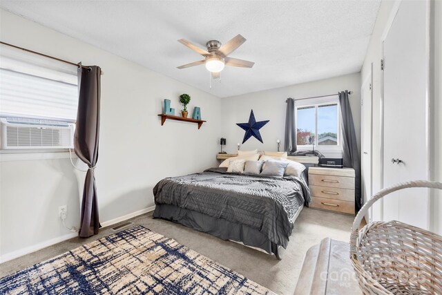 bedroom with a ceiling fan, light carpet, cooling unit, a textured ceiling, and baseboards