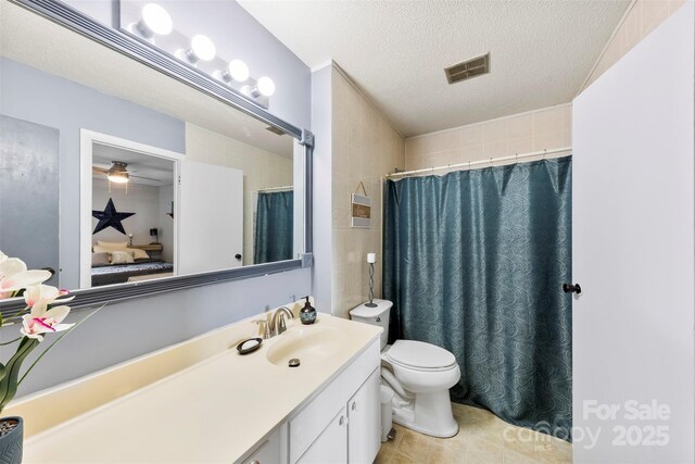 full bathroom featuring vanity, toilet, a textured ceiling, connected bathroom, and visible vents