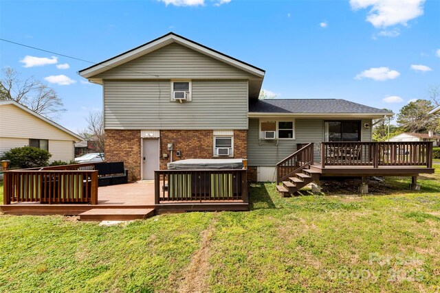 back of property featuring brick siding, a jacuzzi, a wooden deck, and a yard