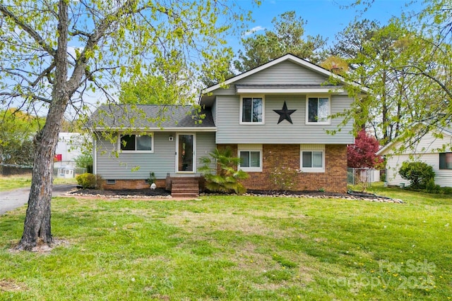 tri-level home with a shingled roof, a front yard, and brick siding