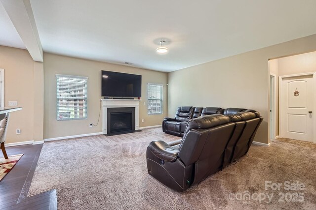 carpeted living room with a fireplace with flush hearth and baseboards