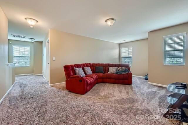 carpeted living area featuring a wealth of natural light, baseboards, and visible vents