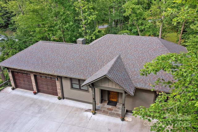 view of front facade with concrete driveway, a shingled roof, and a garage