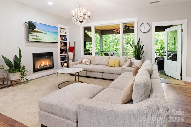 living room with a glass covered fireplace, a chandelier, wood finished floors, recessed lighting, and baseboards