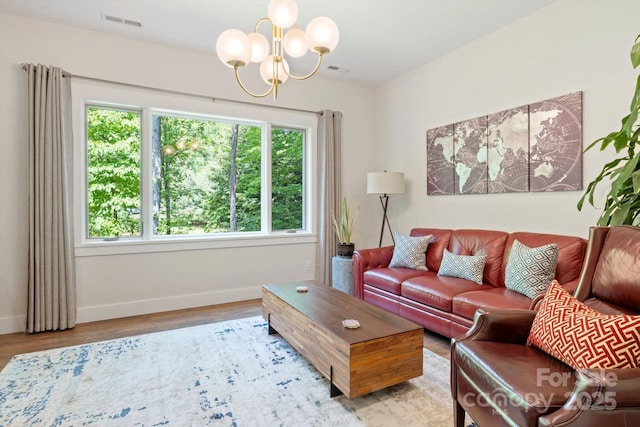 living room featuring a chandelier, baseboards, and wood finished floors