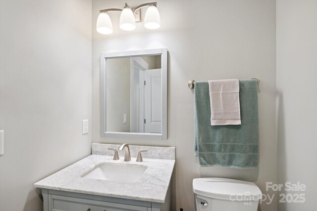 half bath featuring vanity and toilet