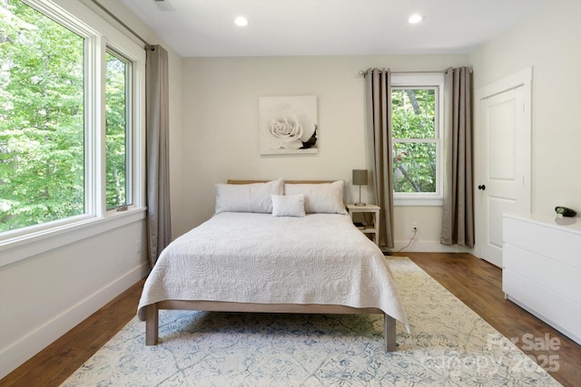 bedroom with multiple windows, wood finished floors, baseboards, and recessed lighting