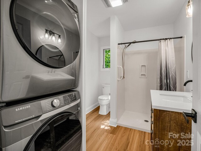 153 Old Lakey Gap Rd, Black Mountain, NC 28711 - full bathroom with stacked washer / drying machine, wood finished floors, a shower with curtain, vanity, and toilet