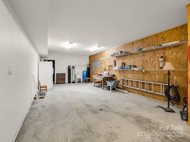 153 Old Lakey Gap Rd, Black Mountain, NC 28711 - garage featuring freestanding refrigerator, wood walls, a workshop area, and gas water heater