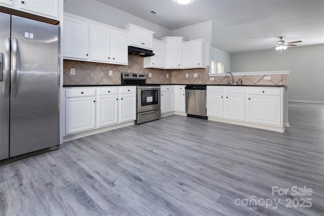 kitchen featuring light wood-style flooring, visible vents, under cabinet range hood, dark countertops, and stainless steel appliances