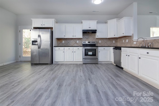 kitchen featuring light wood-type flooring, visible vents, appliances with stainless steel finishes, under cabinet range hood, and dark countertops