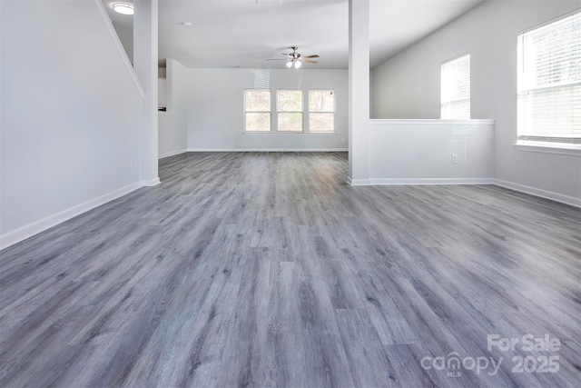 unfurnished living room with ceiling fan, wood finished floors, and baseboards