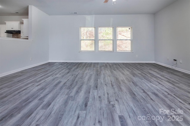 unfurnished room with dark wood-style flooring, baseboards, visible vents, and ceiling fan