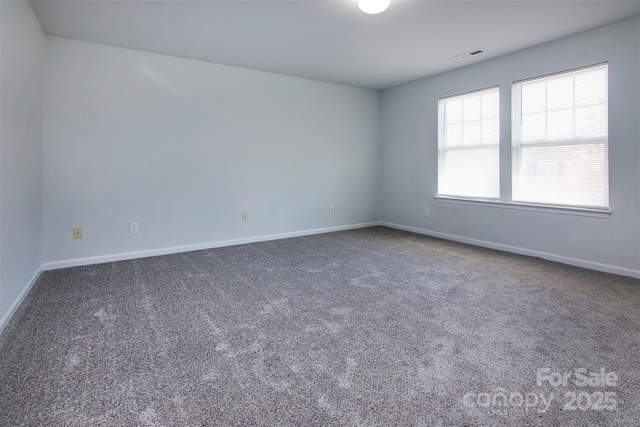 carpeted spare room featuring baseboards and visible vents