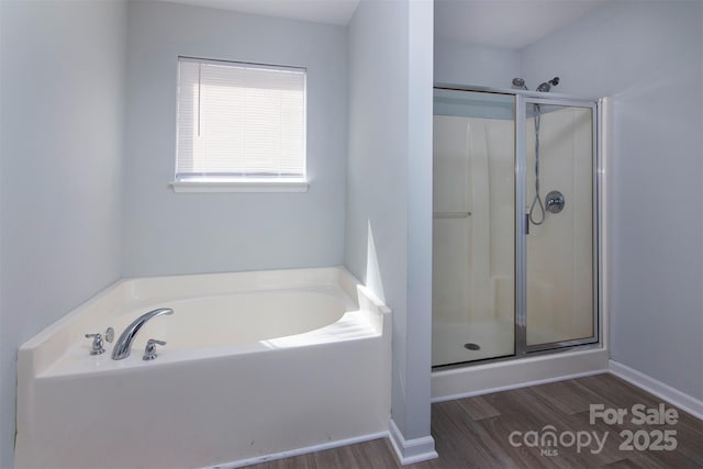 bathroom featuring baseboards, a garden tub, a stall shower, and wood finished floors