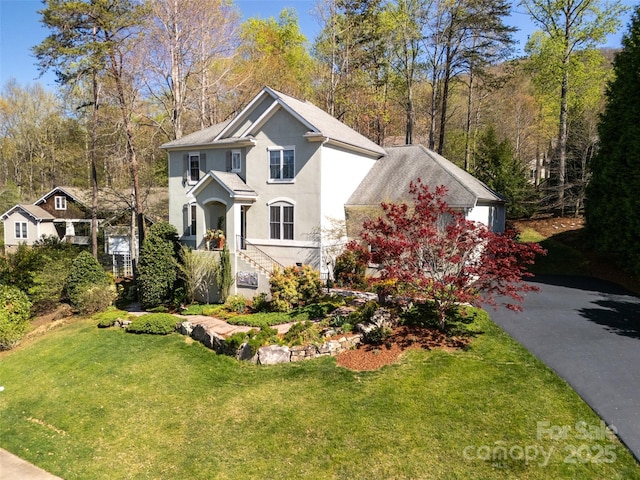 view of front facade with aphalt driveway, stucco siding, and a front lawn