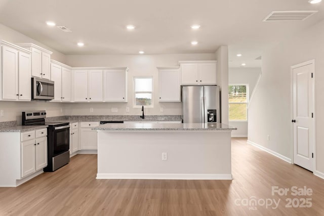 kitchen featuring a kitchen island, a sink, visible vents, white cabinets, and appliances with stainless steel finishes