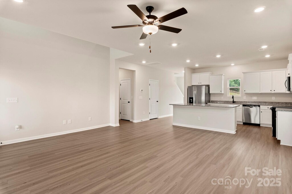 kitchen featuring a kitchen island, light wood finished floors, appliances with stainless steel finishes, open floor plan, and ceiling fan