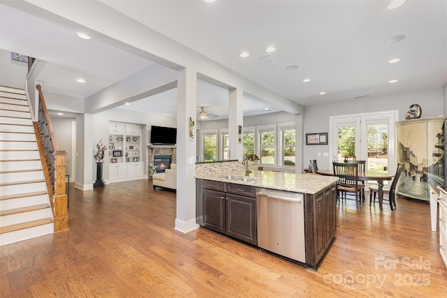 5706 Sardis Hall Ct, Charlotte, NC 28270 - kitchen with a glass covered fireplace, dark brown cabinets, light wood-style floors, a sink, and dishwasher
