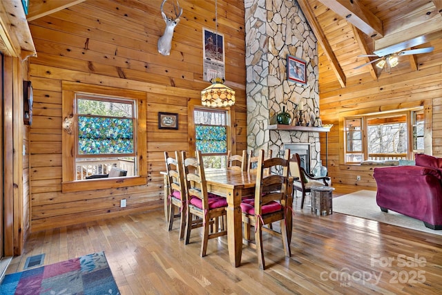 2245 Mckenzie Way N Unit 754, Old Fort, NC 28762 - dining room with hardwood / wood-style flooring, a ceiling fan, a stone fireplace, a wooden ceiling with exposed beams, and wood walls