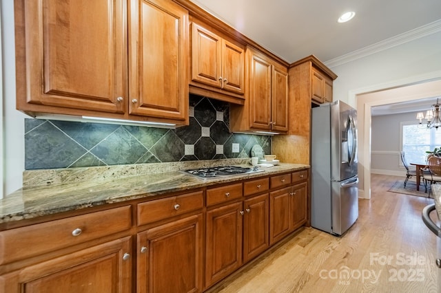 4599 Rustling Woods Dr, Denver, NC 28037 - kitchen with appliances with stainless steel finishes, brown cabinets, light wood-style floors, a chandelier, and stone countertops