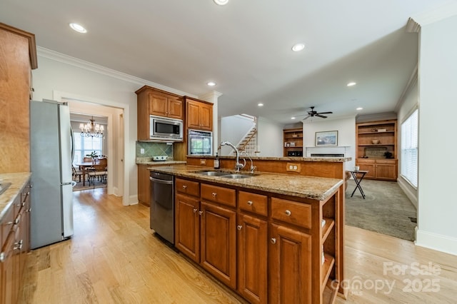 4599 Rustling Woods Dr, Denver, NC 28037 - kitchen with stainless steel appliances, a sink, brown cabinetry, light wood-style flooring, and a fireplace