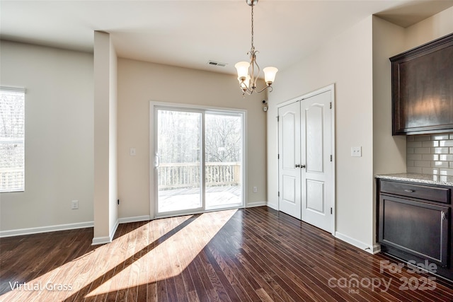 1929 Shorthorn St, Charlotte, NC 28213 - unfurnished dining area featuring baseboards, dark wood finished floors, a chandelier, and plenty of natural light
