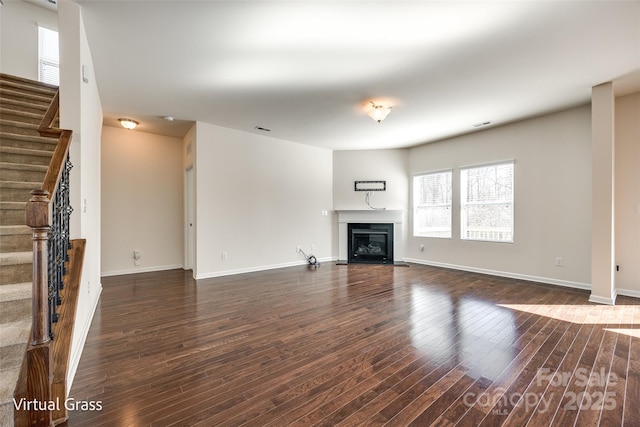 1929 Shorthorn St, Charlotte, NC 28213 - unfurnished living room featuring baseboards, a glass covered fireplace, stairway, and wood finished floors